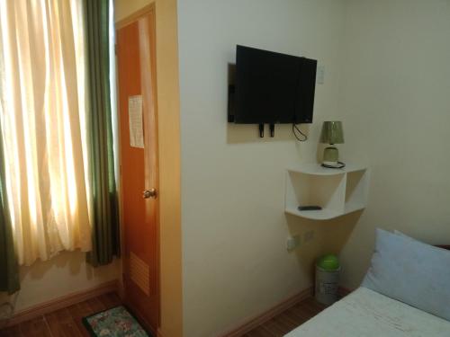 Guinisilibanbucana traveler's inn的卧室设有壁挂式电视和床。