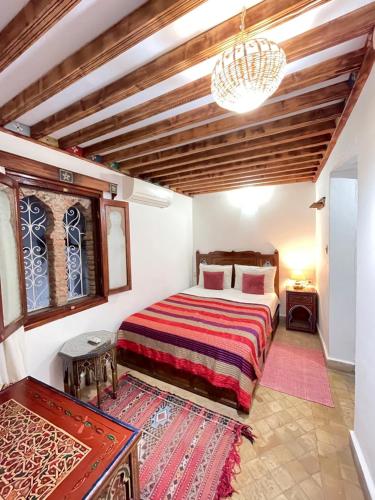 舍夫沙万达尔萨巴巴摩洛哥传统庭院住宅旅馆的一间卧室配有一张床和一个吊灯