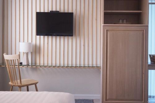 浦阿Shanti-Retreat Hotel的卧室配有带椅子的墙上电视