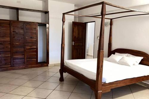 蒙巴萨Mombasa at your doorstep!的卧室配有带白色床单的木制天蓬床