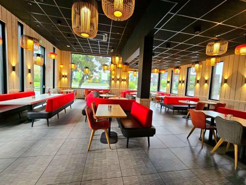 萨莱切Ibis Hôtel Sallanches的一间餐厅,房间内设有红色的椅子和桌子