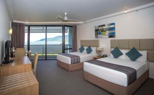 凯恩斯凯恩斯雷吉斯海滨大道度假酒店的酒店客房设有两张床、一张书桌和一个阳台。