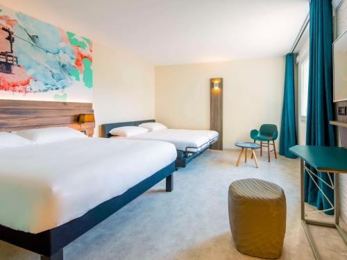萨莱切Ibis Styles Sallanches Pays du Mont-Blanc的酒店客房设有三张床和一张桌子