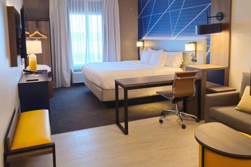 苏福尔斯Comfort Inn & Suites at Sanford Sports Complex的配有一张床和一张书桌的酒店客房