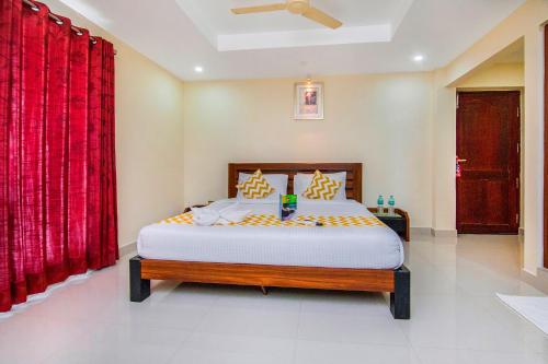 钦奈FabHotel Krishna Residency的一间卧室配有一张带红色窗帘的大床