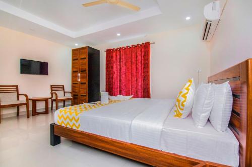 钦奈FabHotel Krishna Residency的一间卧室配有一张带红色窗帘的大床