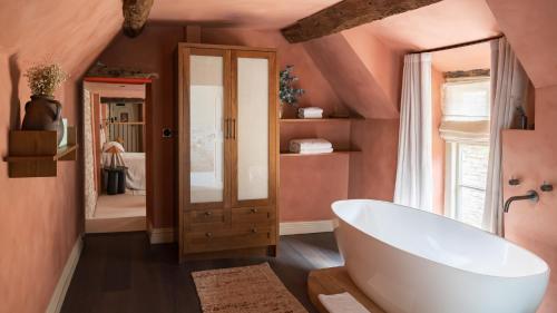 伯福德BULL Burford的一间带大型白色浴缸和粉红色墙壁的浴室