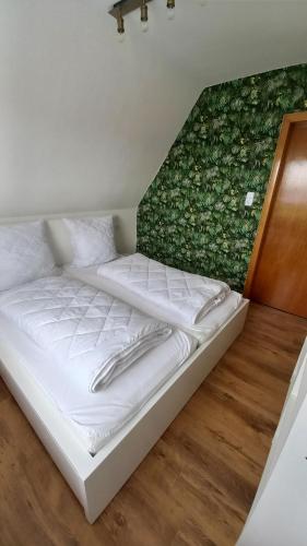 埃姆登Ferienwohnung Dschungel的绿色墙壁的房间里一张白色的床