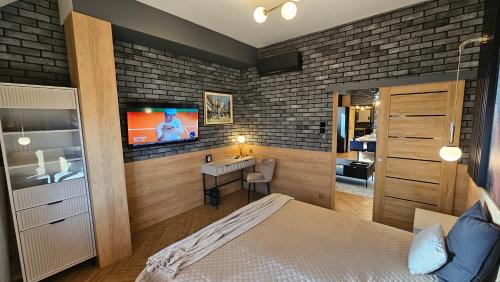 厄尔科Apartamenty Kąpielowa Platynowy的卧室配有1张床和1台砖墙电视