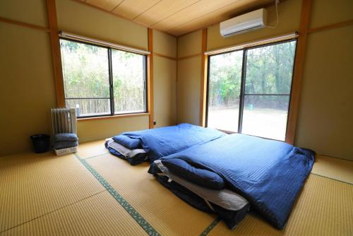 大岛一棟貸しの宿 OKAYADO的一间设有蓝色床的卧室,位于带窗户的房间内