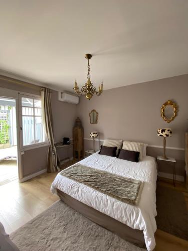比斯卡罗斯La Villa du Grand Large的一间卧室配有一张大床和一个吊灯。