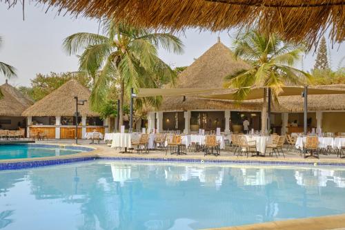萨利波图尔洛亚姆酒店的毗邻度假酒店的带桌椅的游泳池