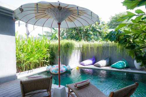 塞米亚克Tropical Beach House Bali的一个带遮阳伞和游泳池的庭院