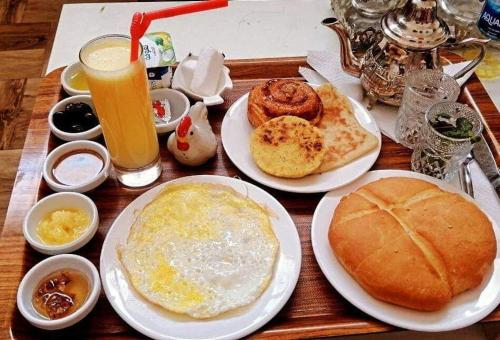 达赫拉Tommy Tour Sahara的一张木桌,上面放着早餐食品和饮料