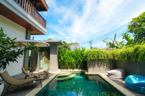 塞米亚克Tropical Beach House Bali的房屋旁的游泳池配有椅子和遮阳伞
