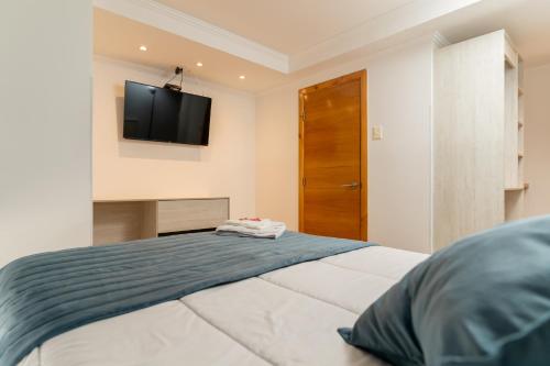 伊基克Hotel Mareblu Iquique的卧室配有一张床铺,墙上配有电视