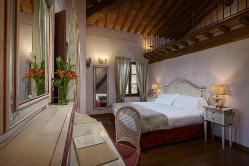 贝托勒拉利奥波尔迪纳酒店的一间卧室配有一张床、一张桌子和一面镜子