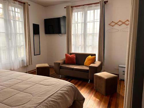 圣地亚哥Casona Lorena的一间卧室配有一张床、一把椅子和电视