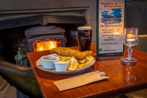 贝提斯顿Reddans of Bettystown Luxury Bed & Breakfast, Restaurant and Bar的一张桌子,上面放着一盘食物和一杯啤酒