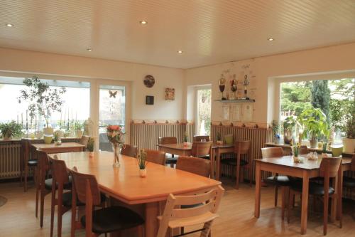特拉本特拉巴赫Pension Bartz的餐厅设有木桌、椅子和窗户。