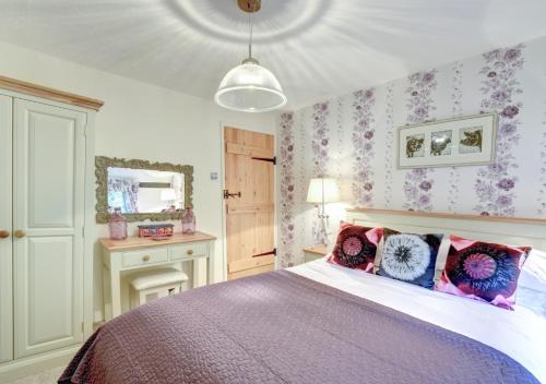 斯科尔The Cottage的一间卧室配有一张带粉色和紫色枕头的床