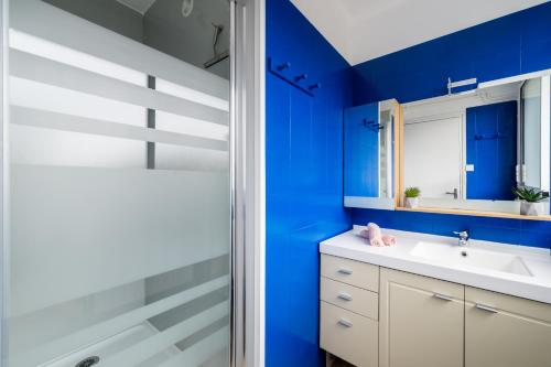 敦刻尔克RDC FACE A LA MER的浴室设有蓝色的墙壁、水槽和淋浴。