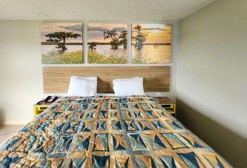 拉斐特Days Inn by Wyndham Lafayette Scott的卧室配有一张墙上三幅画作的床