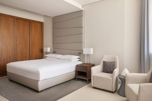 利雅德Marriott Riyadh Diplomatic Quarter的卧室配有白色的床和椅子