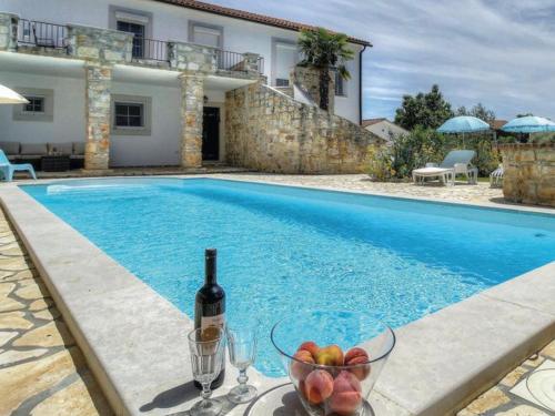 林茨Villa Palma的游泳池旁的一瓶葡萄酒和一碗水果