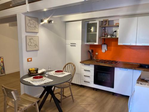 卡塔尼亚Lavica Di Mezzo Apartments的一间带桌椅的厨房和一间带白色橱柜的厨房