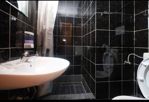 萨拉热窝Uptown Inn的黑色瓷砖浴室设有水槽和卫生间