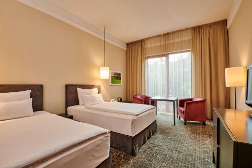 布拉格布拉格NH精选酒店的酒店客房设有两张床和一张桌子。