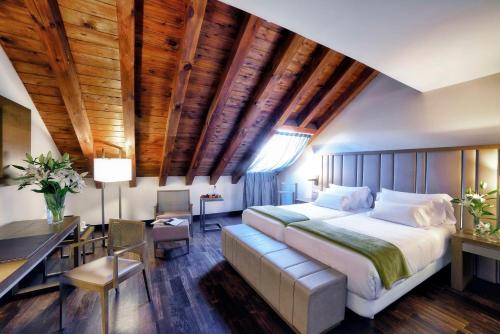 马德里帕拉西奥特帕NH精选酒店的一间卧室配有一张大床、一张桌子和一张桌子