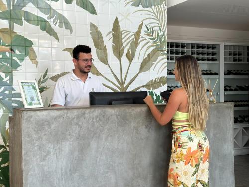 卡波布里奥Passagem Concept Hotel e Spa的一名与男子一起在现金登记册上登记的女性