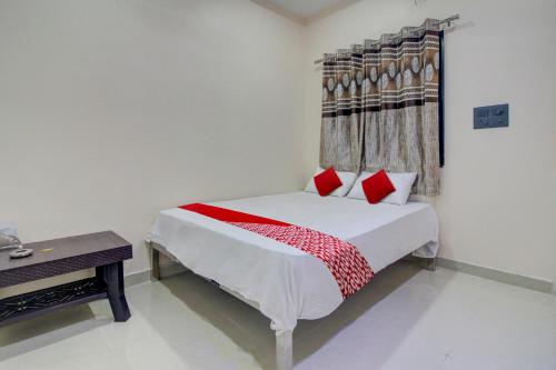 那格浦尔OYO Flagship Hotel Roman Inn的一间卧室配有一张带红色枕头的床和一张桌子