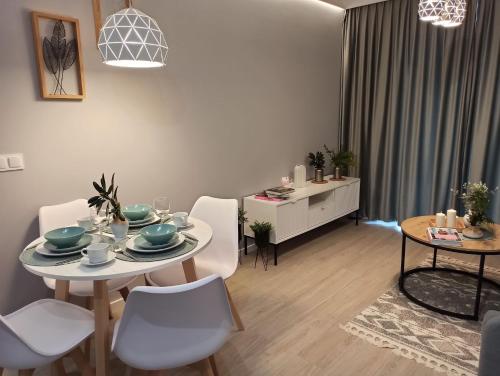 格丁尼亚Apartament Grabówek的客厅配有桌子和白色椅子
