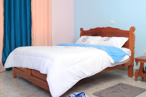 NguluniKoma Gardens and Resort的一间卧室配有一张带白色床单的木床