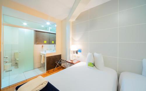拉巴斯LP哥伦布酒店的卧室配有白色的床和淋浴