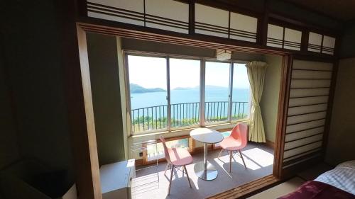 伊喜末HOTEL GREEN PLAZA SHODOSHIMA - Vacation STAY 46464v的一间卧室设有一张桌子和椅子的阳台