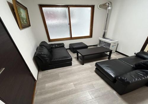 小樽Ota Apartment - Vacation STAY 16060的客厅配有黑色皮革家具和窗户