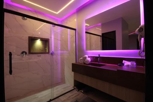 里梅拉Motel Deslize Limeira 2的浴室设有紫色照明、水槽和淋浴