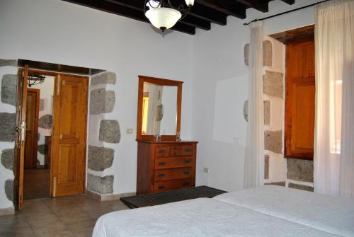 阿古伊梅斯Casa Rural Los Suárez的一间卧室配有一张床、梳妆台和镜子