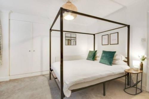 皇家滕布里奇韦尔斯Central 2 bedroom garden flat with free parking的一间卧室配有一张带绿色枕头的天蓬床
