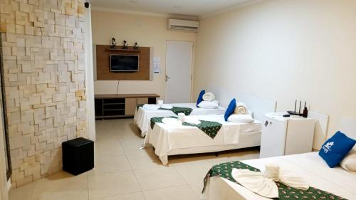 布罗塔斯Brotas Suítes Belo Quinto & Spazzio Bloco 2的酒店客房设有三张床和电视。