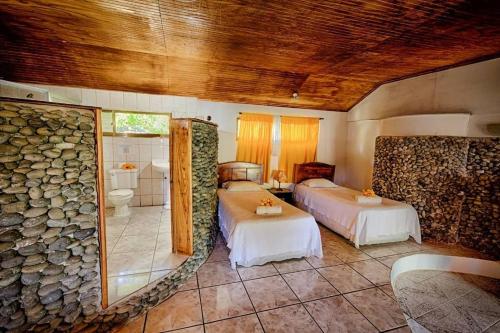 安加罗阿Hotel Chez Maria Goretti的一间卧室设有两张床和石墙