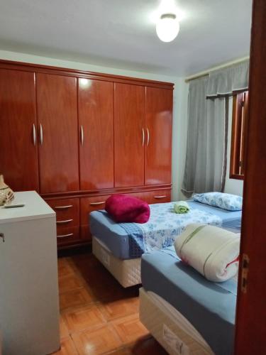 新汉堡市Apartamento das Azaléias térreo的一间卧室设有两张床和木制橱柜。