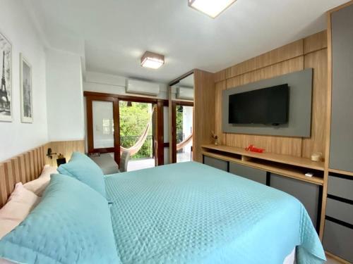 本图贡萨尔维斯Villaggio dos Vinhedos的一间卧室配有蓝色的床和一台平面电视