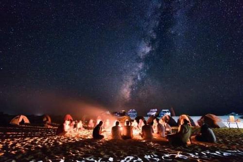 BawatiAbo Yusre Sfari的一群人晚上坐在海滩 ⁇ 火旁