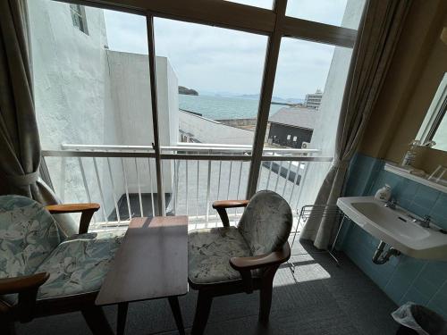 土庄町入舟旅馆的客房设有椅子、水槽和窗户。