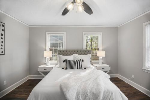 奥古斯塔Forest Hills Cottage的一间白色卧室,配有床和2个窗户